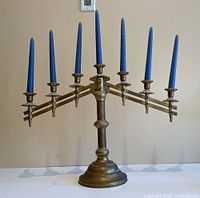 Full view of vintage seven-arm brass candelabra with seven blue candles, showing overall structure and size.