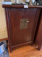 Full view of the wood cabinet closed showing front doors and latch.