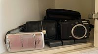 Canon PowerShot G7 and S50 cameras with cases and extra batteries on a shelf.