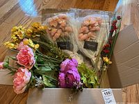 Box with multiple faux flower stems including pink peonies, red and yellow flowers, and green leaves along with two Kamang faux flower packages