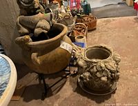 Photo of the outdoor fountain and decorative plant pot side by side on a basement floor, showing overall shape and condition.