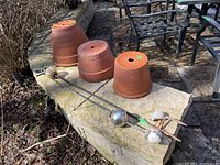 Three terracotta garden pots on a stone ledge, orange color, with drainage holes and wear