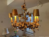 Front view of the metal floral chandelier showing its six lampshades and detailed vine-like arms with flowers.