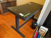 Front angle view showing black desktop surface, wireless charger on corner, and sturdy metal frame legs.
