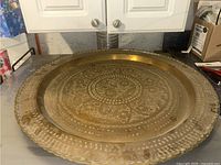 Full view of large round metal tray showing overall shape, size and scalloped edge.