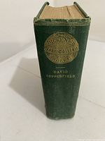 Spine of the book showing the gold stamp 'Dickens's Globe Edition Works' and 'David Copperfield' title on green cloth cover.