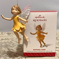 Hallmark Keepsake Daffodil Fairy ornament hanging suspended in front of its original box showing front view and packaging details