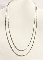 Necklace shown draped on a mannequin displaying the wrap-around length and design with alternating bead and rod pattern.