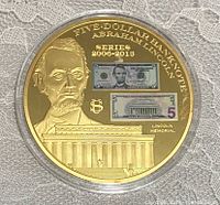 Obverse side of the commemorative coin showing Abraham Lincoln, Lincoln Memorial, and two embedded images of the 5 dollar banknote.