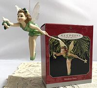 Photo of the hanging Mistletoe Fairy ornament next to its original red Hallmark Keepsake box showing the fairy in a green dress with translucent wings.