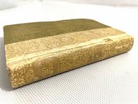 Front and spine view of the vintage book showing decorative gold floral embossing with text 'Idylls of the King' on spine