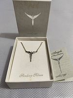 Necklace displayed in original white box with silver angel logo and included informational brochure.