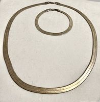 Full view of necklace and bracelet laid flat on white background, showing matching design and clasp style.