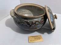 Side view of open handmade stoneware porcelain soup tureen showing interior and separate lid with glaze pattern and decorative motifs.