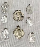 Overview of 6 vintage religious medallions including Pope Paul VI, Virgin Mary, and Madonna and Child designs, some sterling silver, all showing wear.