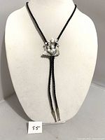 Front view of the vintage sterling silver bolo tie with desert and night motifs on black braided leather cord