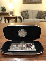 Black display case opened to show the silver-colored medallion coin in a clear capsule and the Denis Potvin NHL All-Stars stamp inside.