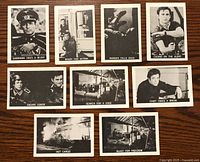 Front side of 9 Garrison's Gorillas 1967 trading cards arranged on a wooden surface showing a mix of character portraits and action shots in black and white.