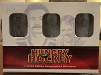 Original packaging box showing window cutouts with glasses visible and artist illustrations of the players on the box front. Contains autographs and title 'Hungry for Hockey Limited Edition Autographed Collection'.