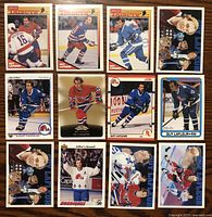 Photo of 12 assorted Guy Lafleur hockey cards spread out on wooden surface. Cards show various poses and uniforms including Montreal Canadiens and Quebec Nordiques.