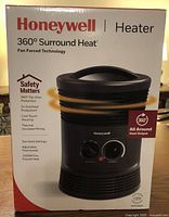Box front showing Honeywell 360° Surround Heat fan forced heater with key features including safety protections, adjustable thermostat, and power rating.