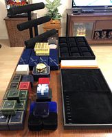 Shows a variety of velvet and leather jewelry boxes and organizers, black velvet multi-tiered T-bar display stand for bracelets and watches, and two large black velvet trays with multiple compartments.
