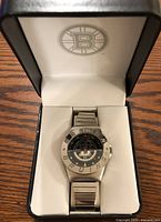 Front view of the watch inside the original watch case showing the Boston Bruins logo on the lid and the watch face.