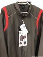 Front view of the black North End windbreaker jacket showing standout red and grey color accents, quarter zipper, and attached tags.