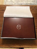 Polished wooden case with RCM logo on top, shown with protective covering still partly on.