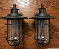 Two black metal carriage lights with hand blown bubble glass inserts shown from the front.