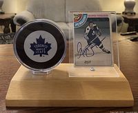 Front side of the wooden display showing Toronto Maple Leafs puck in protective case and autographed George Ferguson hockey card in acrylic holder.