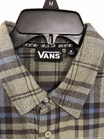 Close-up of the collar and VANS label inside the shirt, showing size medium and new condition with tags.
