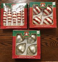 Three original boxed sets of Santa's Trim Shoppe hand decorated glass ornaments; one set of elongated red and white striped, one set of round red and white striped, one set of white with gold glitter trim.