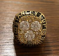 Front view showing three large clear crystal stones with surrounding smaller stones and text 'STANLEY CUP 1987-88'.