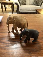 Two wood carved elephants on a wooden table with couch and chairs in background