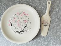 Plate and cake server set showing floral pattern on white ceramic surface.