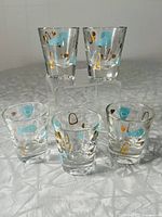 Full set of five vintage shot glasses in Atomic Amoeba pattern displayed on a reflective surface.