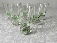 Front angle view of six green bubble glass shot glasses arranged in two rows.