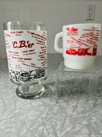 Two CB-themed glasses displayed on a countertop, one white milk glass mug and one clear glass, showing overall lot contents.