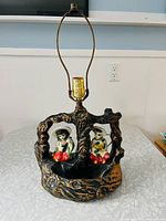 Full view of vintage mid-century ceramic lamp with tree-stump style base and boy and girl figurines, showing brass lamp hardware and planter area.