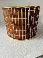 Front view of mid-century modern lampshade showing walnut interlace wood with brass framing.