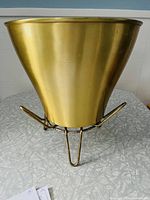 MCM gold exterior planter with metal hairpin leg stand, showing overall shape and finish