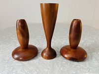 Front view of three wooden candle holders on a light surface, showing the different shapes and sizes.