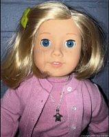Close-up of the doll's face, hair, necklace, and pink cardigan sweater.