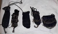 All five antique beaded purses laid out on white quilted surface showing varying styles and beadwork.