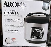 Front of the box showing Aroma Rice & Grain Cooker 8 Rice Cups Cooked, 2 Quarts capacity, sensor logic technology, versatile and one-pot meals features.
