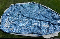 Pool liner laid out on grass showing blue mosaic interior pattern