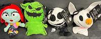 Four plush clip keychains of Nightmare Before Christmas characters from left to right: Sally, Oogie Boogie, Jack Skellington, and Zero, all approximately 6 inches tall, brand new with tags.
