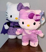 Front view of both Hello Kitty plush toys, the pink mummy side stepper in front and purple vampire greeter behind.