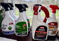 Multiple new garden chemical spray bottles on a surface, labeled mainly ACE and Ortho